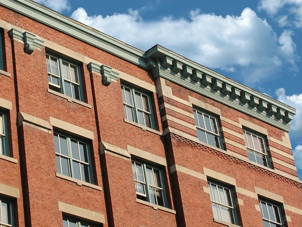 Upper brick facade with a projecting cornice and repeated window surrounds
