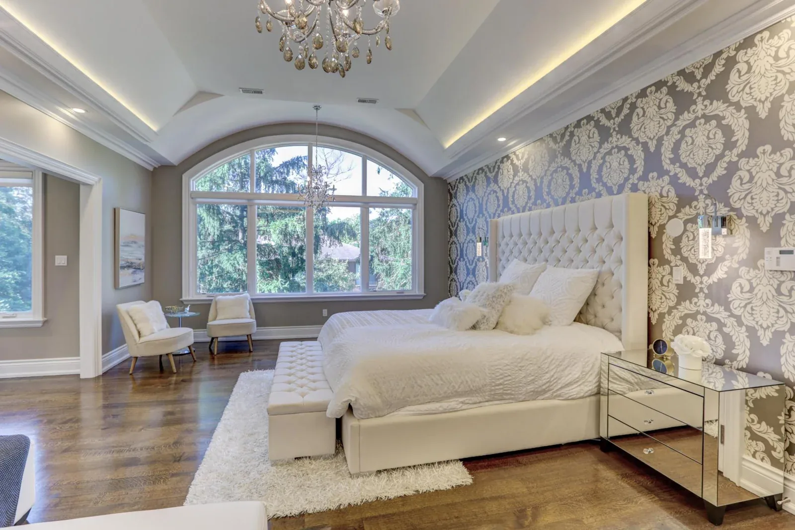 Bedroom with an arched window and illuminated ceiling details