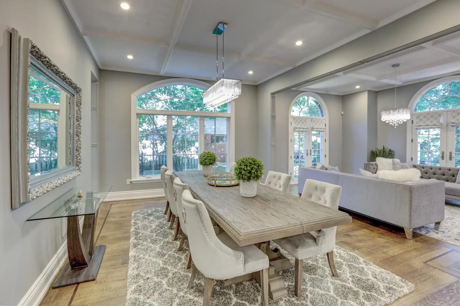 Dining and living area with arched windows and ceiling moulding
