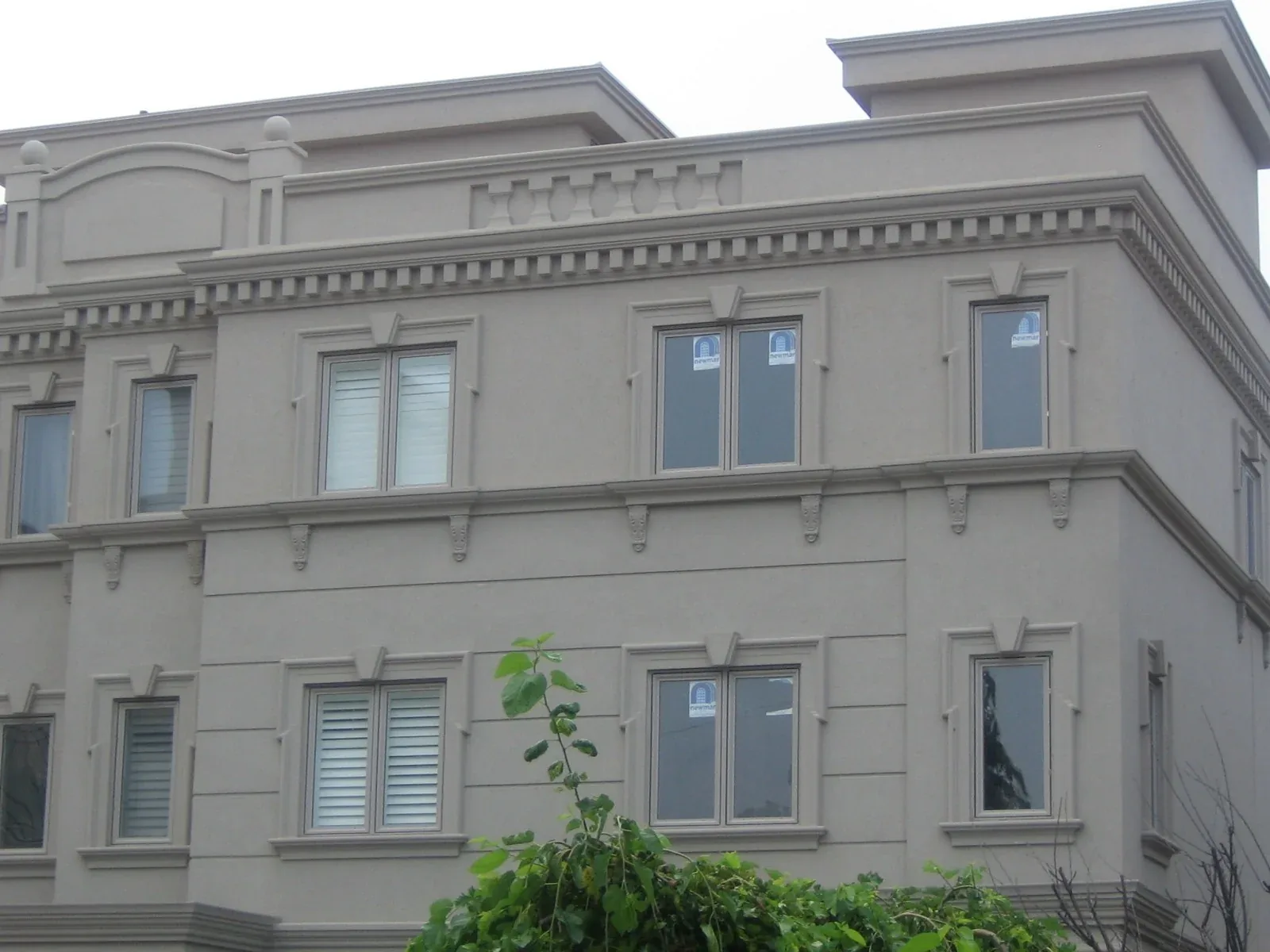 Pale residential facade with decorative brackets and horizontal bands