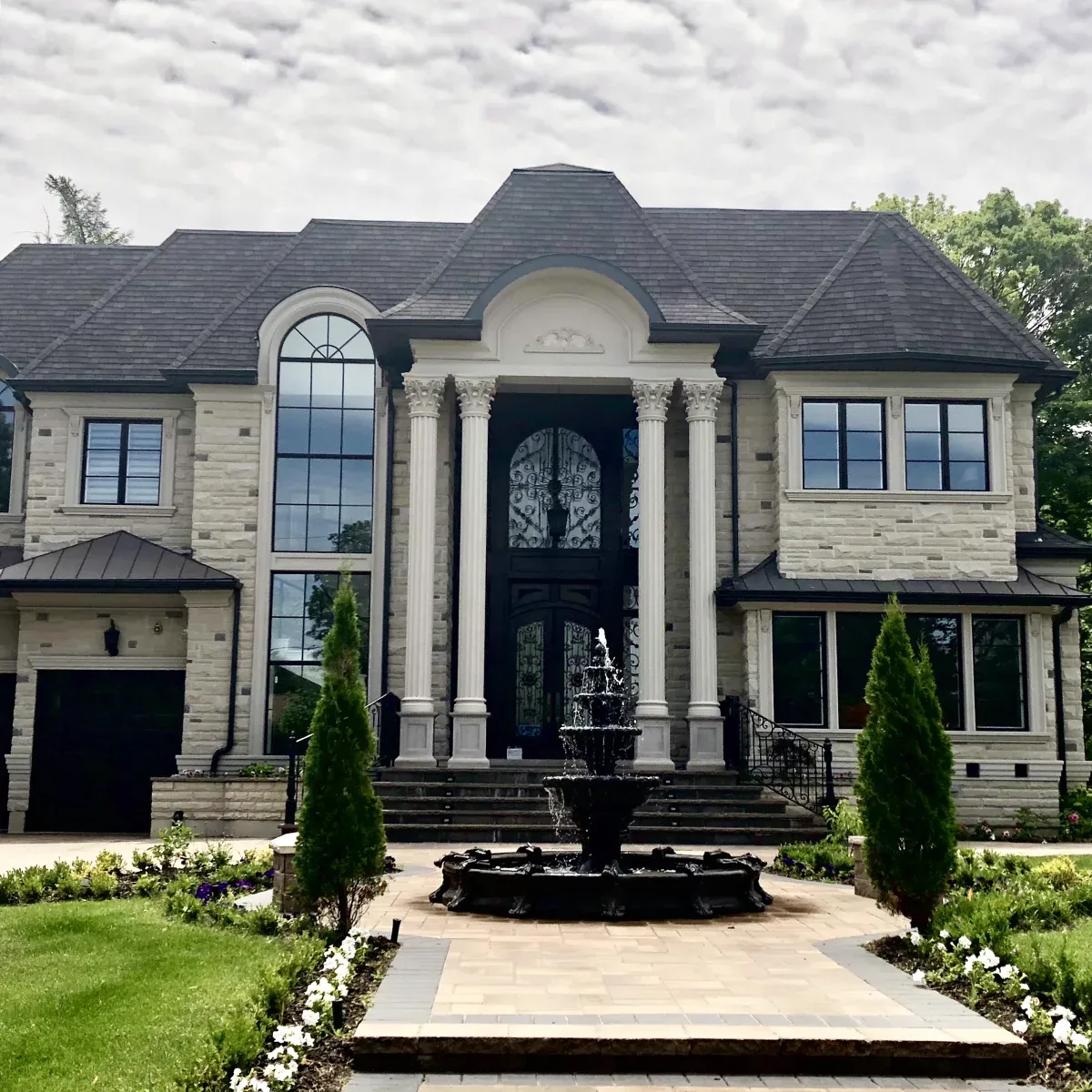 A symmetrical entrance, tall arched glazing, fluted columns and carefully framed upper windows bring a strong vertical rhythm to this stone residence.