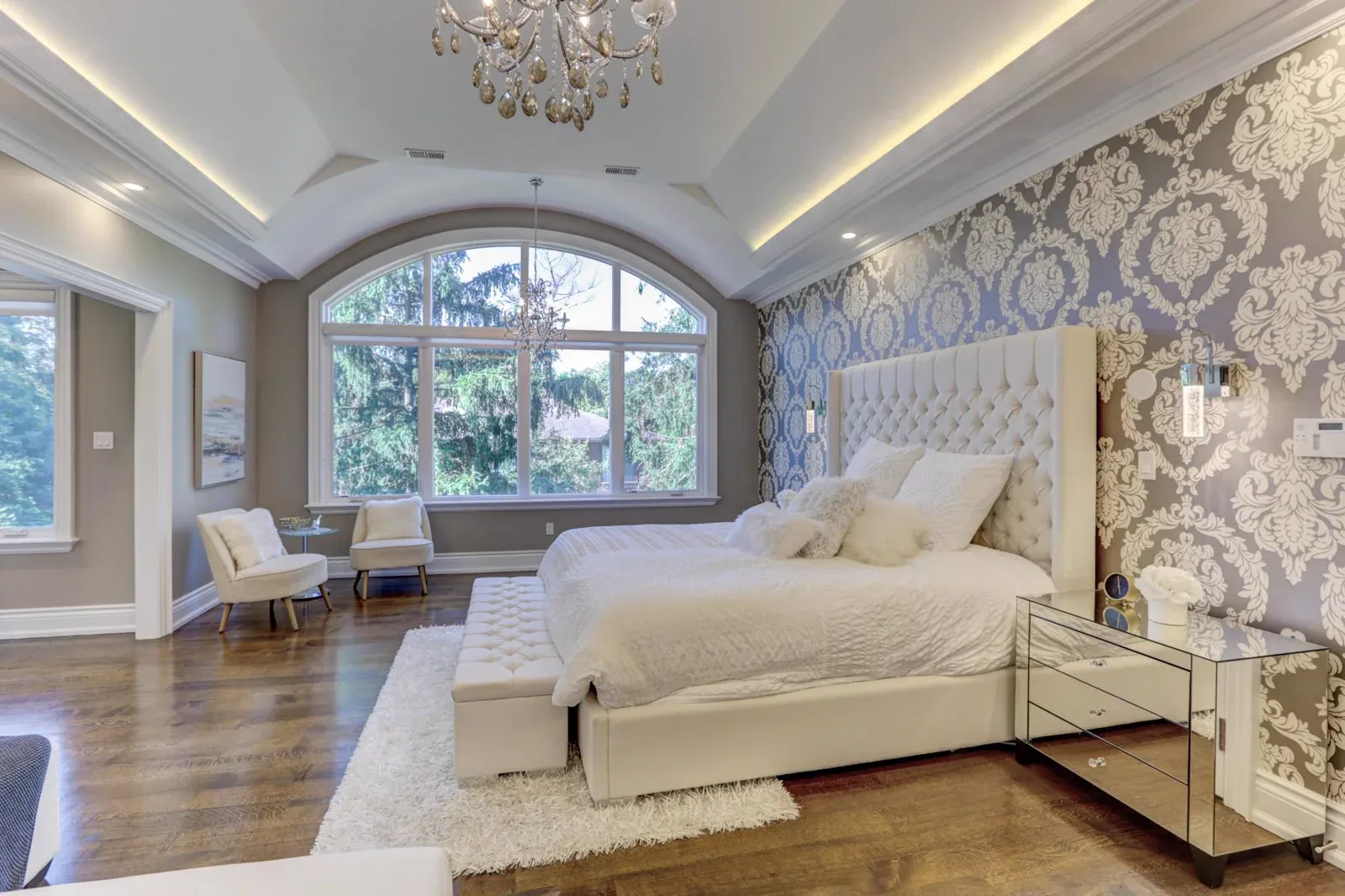 Layered ceiling moulding follows the left and right edges of this bedroom, framing the room with a continuous architectural line.