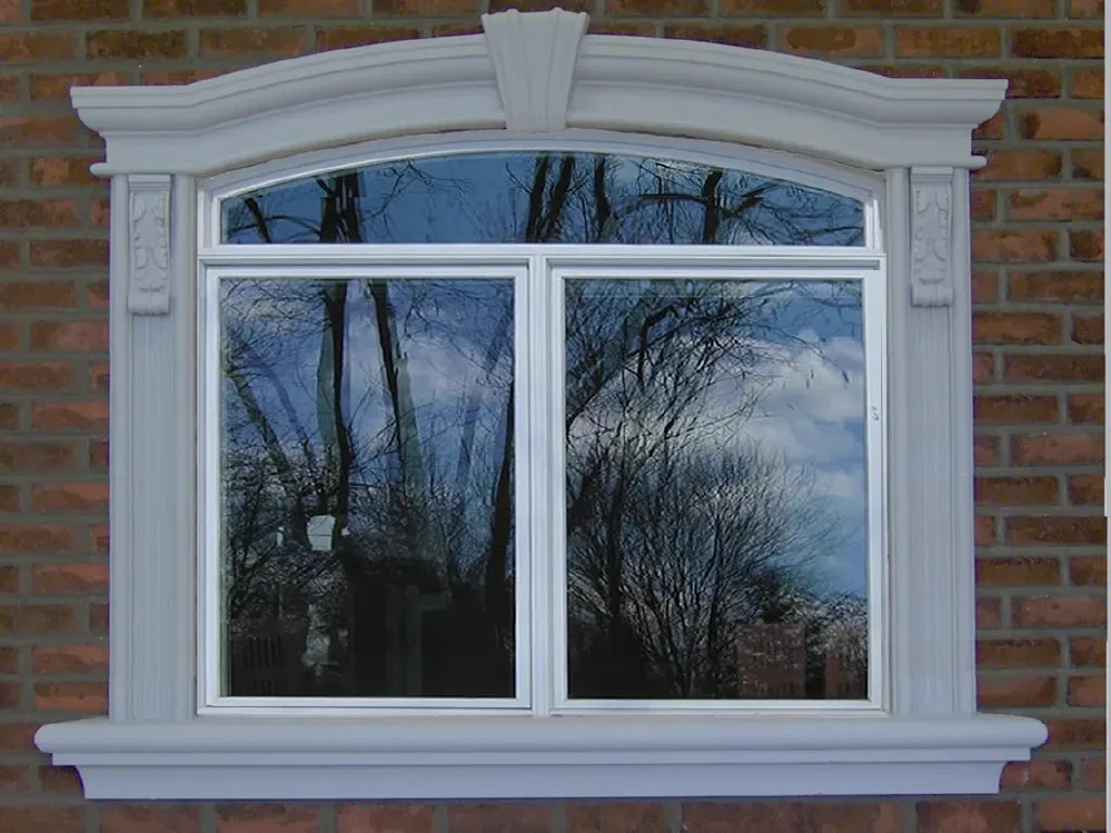 Exterior window framed by a curved header, keystone, pilasters and sill
